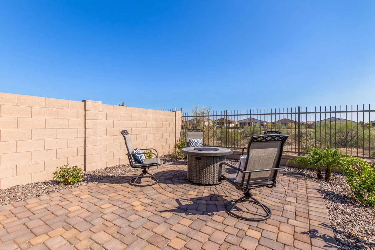 A welcoming patio with cozy seating wrapped around a fire pit, set against landscaped greenery. The area is ideal for relaxing evenings, stargazing, or gathering with friends and family in a private backyard setting.