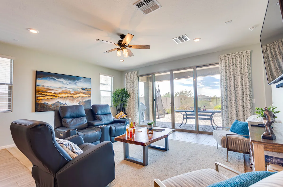 A cozy seating area is arranged near large windows, letting in natural light and offering views outside. The inviting space is ideal for relaxing, socializing, and watching sunsets, suggesting a connection between the interior setting and the surrounding neighborhood.