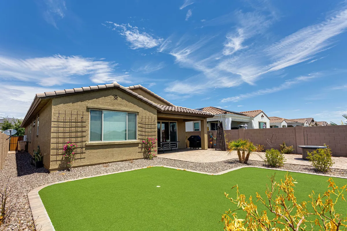 A cheerful backyard scene featuring well-maintained artificial grass, vibrant flowering plants, and modern outdoor furniture. The south-facing yard offers privacy, with ample space for pets to play and guests to unwind.