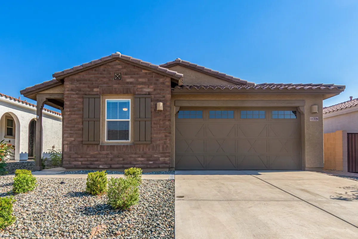 A welcoming exterior shot of the home’s brick facade, featuring shuttered windows and a garage door—hinting at ample storage for golf gear and easy access for returning from the course. The inviting mood suggests the start or end of a day filled with activity.