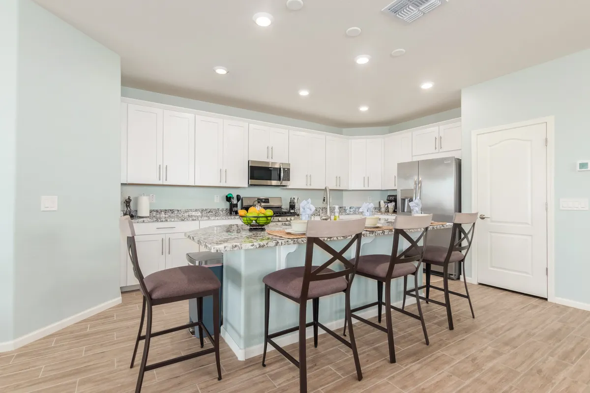 This image features a welcoming kitchen with an island countertop, bar stools, and appliances, set up for cooking, entertaining, and casual family dining. The open layout hints at communal gatherings and shared meals, key themes in the section.