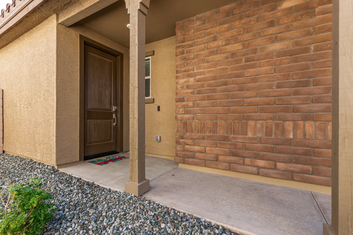 A welcoming front entrance with a brick wall, pathway, and decorative mat, inviting residents and guests into the home. The view hints at a friendly, safe neighborhood atmosphere, perfect for daily strolls with a pet.